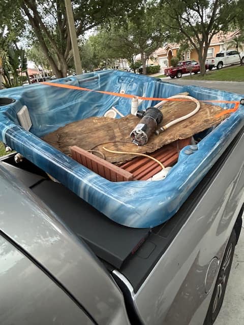 A dismantled hot tub shell strapped into the Gym Junksters truck bed after removal from a South Florida back yard